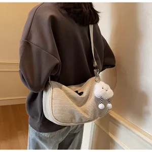 Detail of off-white corduroy dumpling crossbody bag with cute cloud plush charm accessory