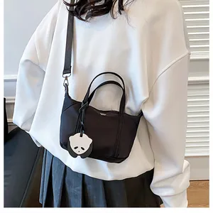 Model wearing a black mini dumpling bag with a cute panda pendant and thin strap