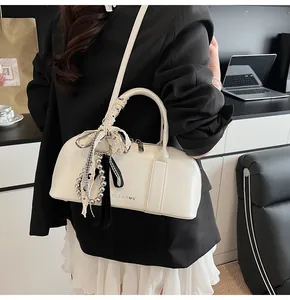 Detalle de un bolso de charol crema con un lazo elegante de encaje blanco y negro