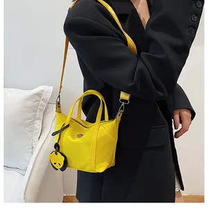 Bright yellow nylon dumpling bag shown on black blazer with panda charm detail