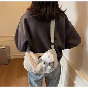 Off-white corduroy hobo bag on model with cute cloud plush charm and wide strap