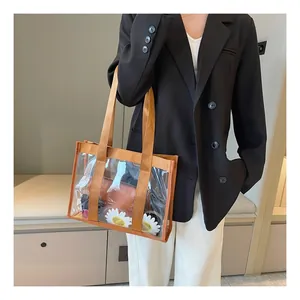 Close-up of transparent PVC tote bag with orange canvas straps and a brown inner pouch