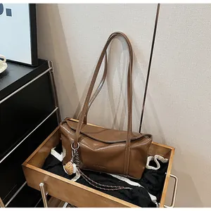 Detailed top view of large dark brown leather shoulder bag with decorative charm on wood