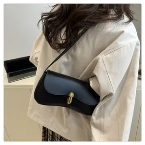 Detail of a chic black shoulder bag with a sleek gold metal buckle worn by a model