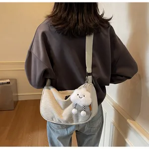 Detail of cream corduroy dumpling bag with plush cloud charm and wide strap