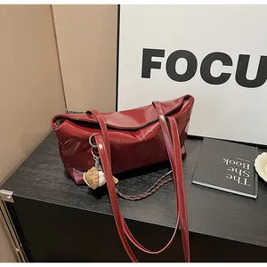 Detail view of burgundy faux leather tote bag with glossy finish and baseball glove charm