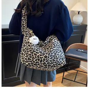 Détail du sac hobo léopard avec un pendentif monstre en peluche blanche
