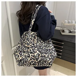 Detailed back view of a large leopard print canvas tote bag worn by a model