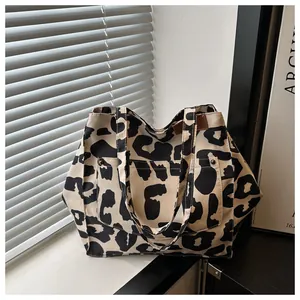 Detailed view of leopard print canvas tote bag with front pocket and rivet accents