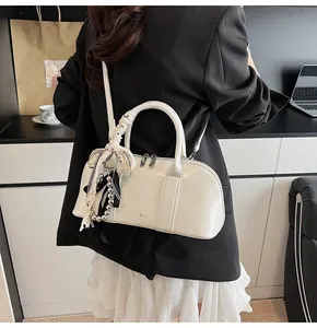 Detalle de un bolso Boston blanco crema con lazo de encaje y cuentas en una modelo