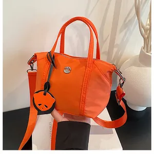 Detail of bright orange nylon dumpling bag with adjustable strap and cartoon charm