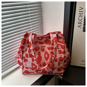 Close-up of pink and red leopard print canvas tote bag with metal rivet pocket detail