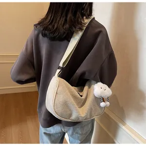Detail of cream corduroy crossbody bag with soft cloud plush charm and wide strap