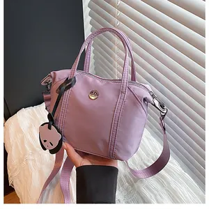 Close-up of lavender nylon dumpling bag with circular logo and cute panda pendant