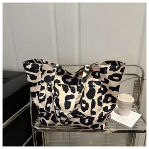 Detail of large canvas tote bag with cow print pattern and metal rivet reinforcements
