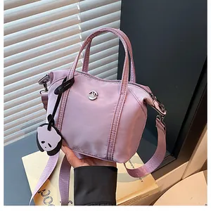 Detail of lavender nylon dumpling bag featuring fashion logo and panda charm accessory