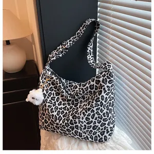 Gros plan d'un sac cabas en toile léopard avec bandoulière et breloque en peluche