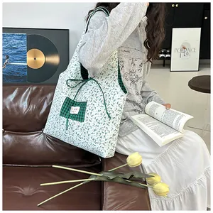 Detail of floral canvas tote bag featuring green checkered pocket and ribbon tie closure