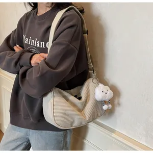 Detail of beige corduroy dumpling bag featuring a cute white cloud plush pendant charm