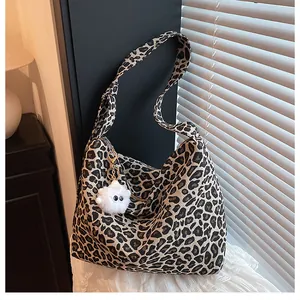 Détail du sac fourre-tout léopard avec breloque monstre en peluche et large bandoulière