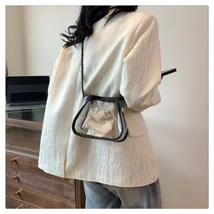 Detail of transparent PVC crossbody bag with black trim and cream drawstring inner pouch
