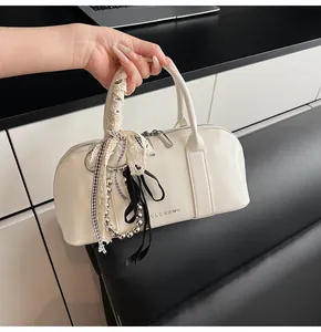 Detalle del bolso Boston crema con cintas de encaje, bufandas de cuadros y cadenas metálicas