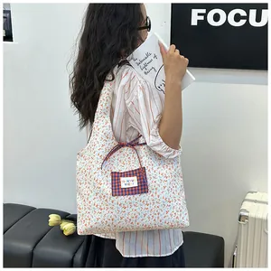 Detail of floral tote bag with a blue checkered pocket and decorative ribbon accent