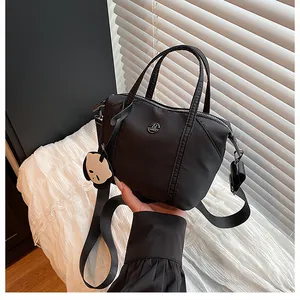 Detail showing black nylon dumpling bag with round logo and cute panda pendant charm