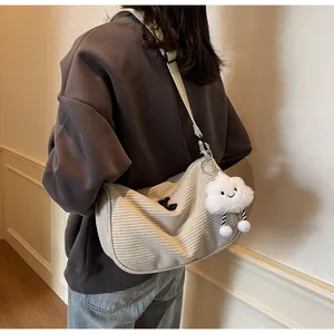 Detail of beige corduroy dumpling bag featuring adjustable strap and plush cloud charm