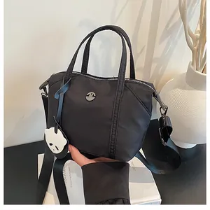 Detail of black nylon dumpling bag with cute panda charm and wide shoulder strap