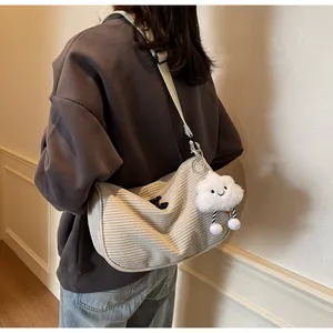 Detail view of beige corduroy crossbody bag with cloud charm on model's shoulder