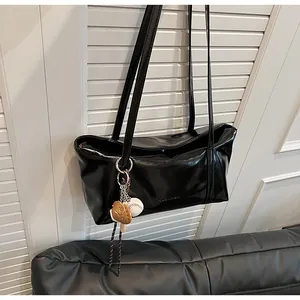 Close-up of black waxed leather shoulder bag with gloss finish and baseball keychain charm