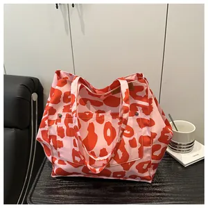 Detail of red leopard print canvas tote bag with front pocket on wood surface