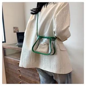 Detailed side view of a clear PVC crossbody bag with green trim and beige canvas inner pouch
