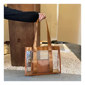Detail view of transparent PVC tote bag with brown nylon handles and inner pouch