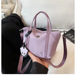 Detailed shot of purple nylon dumpling bag with adjustable strap and panda charm