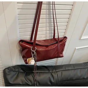 Detail of burgundy wax leather shoulder bag with creative baseball glove charm