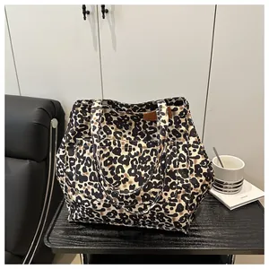 Detail of leopard print canvas tote bag featuring a large front pocket and brown leather tag