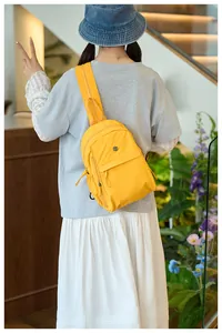 Detail of yellow nylon crossbody bag with adjustable strap and decorative logo patch