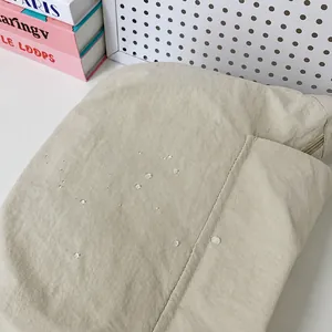 Dettaglio del tessuto beige impermeabile con gocce d'acqua e trama a pieghe fini
