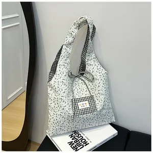 Close-up of floral tote bag with gingham pocket and rainbow letter brand label