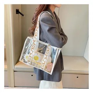 Macro shot of large clear PVC tote bag featuring white daisy pouch and wide logo strap