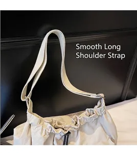 Detail of creamy white nylon crossbody bag showing smooth strap and drawstring texture