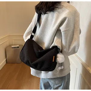 Detail of black corduroy messenger bag with wide strap and white plush cloud charm