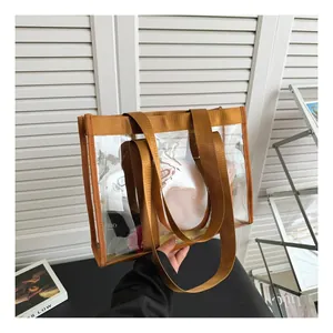Detail of transparent PVC tote bag with brown nylon straps held in a bright setting