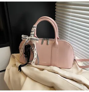 Detalle de bolso rosa con lazo de cinta, colgante plateado y logotipo de Clear K