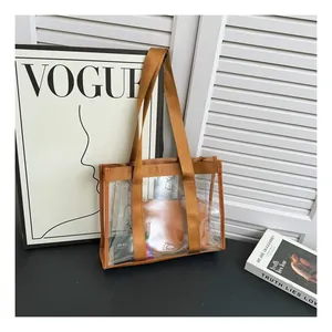 Detailed close-up of transparent PVC tote bag featuring brown nylon straps and inner pouch