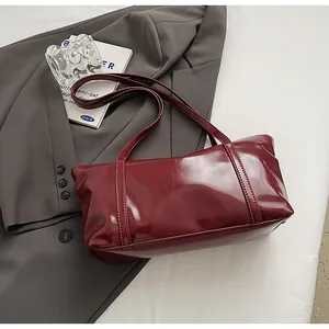 Detail of burgundy glossy oil wax leather handbag on a professional studio backdrop