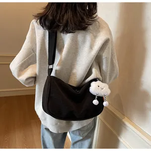 Detail of black corduroy crossbody bag with cute plush cloud charm on a casual model