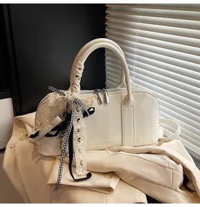 Detalle del bolso Boston de charol blanco con adornos de encaje y herrajes plateados